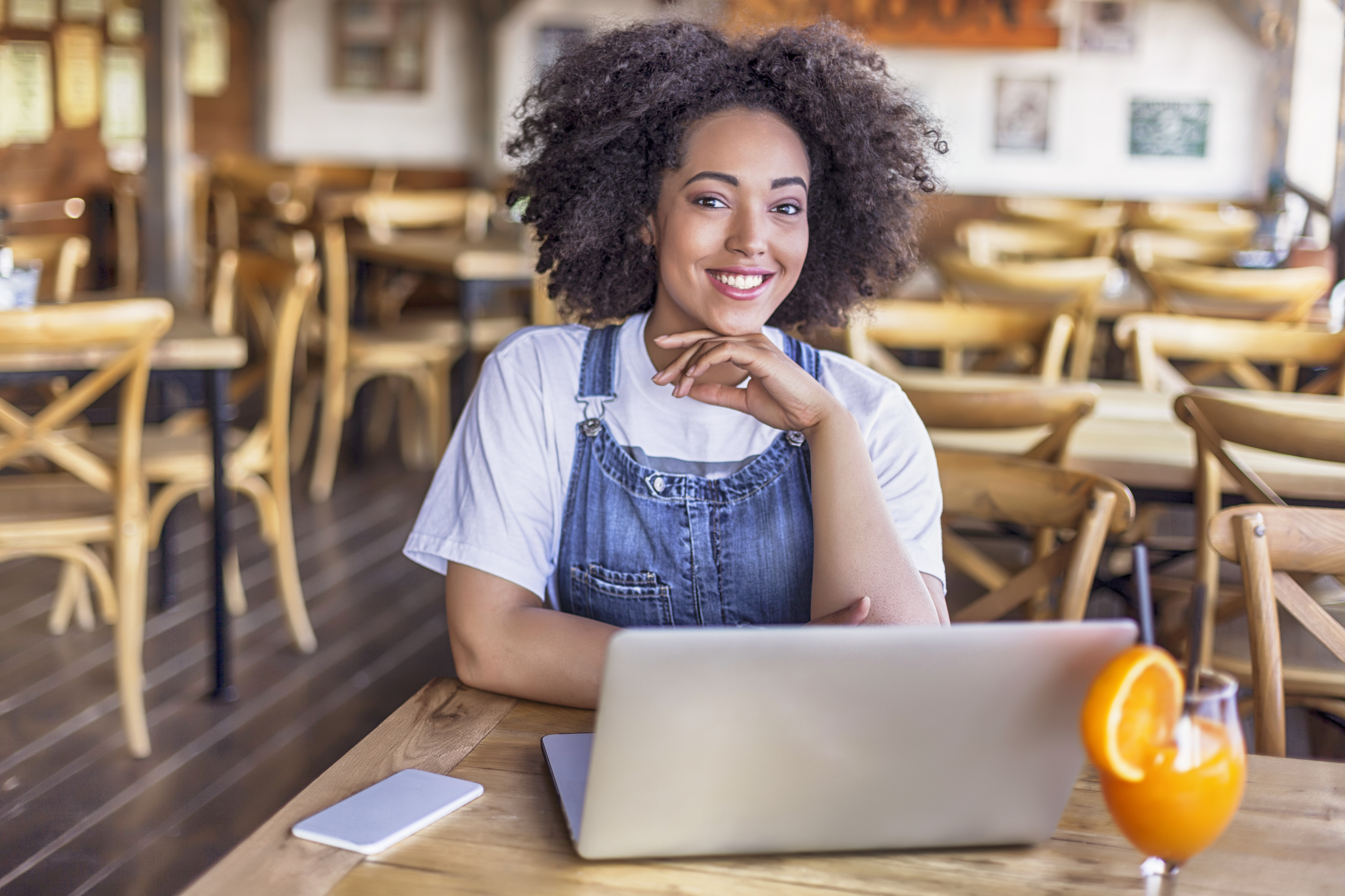 Smiling african woman using laptop in cafeteria