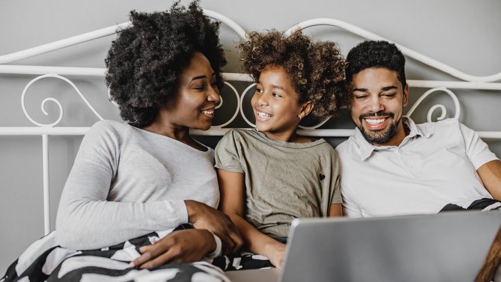 African American family using laptop in bed